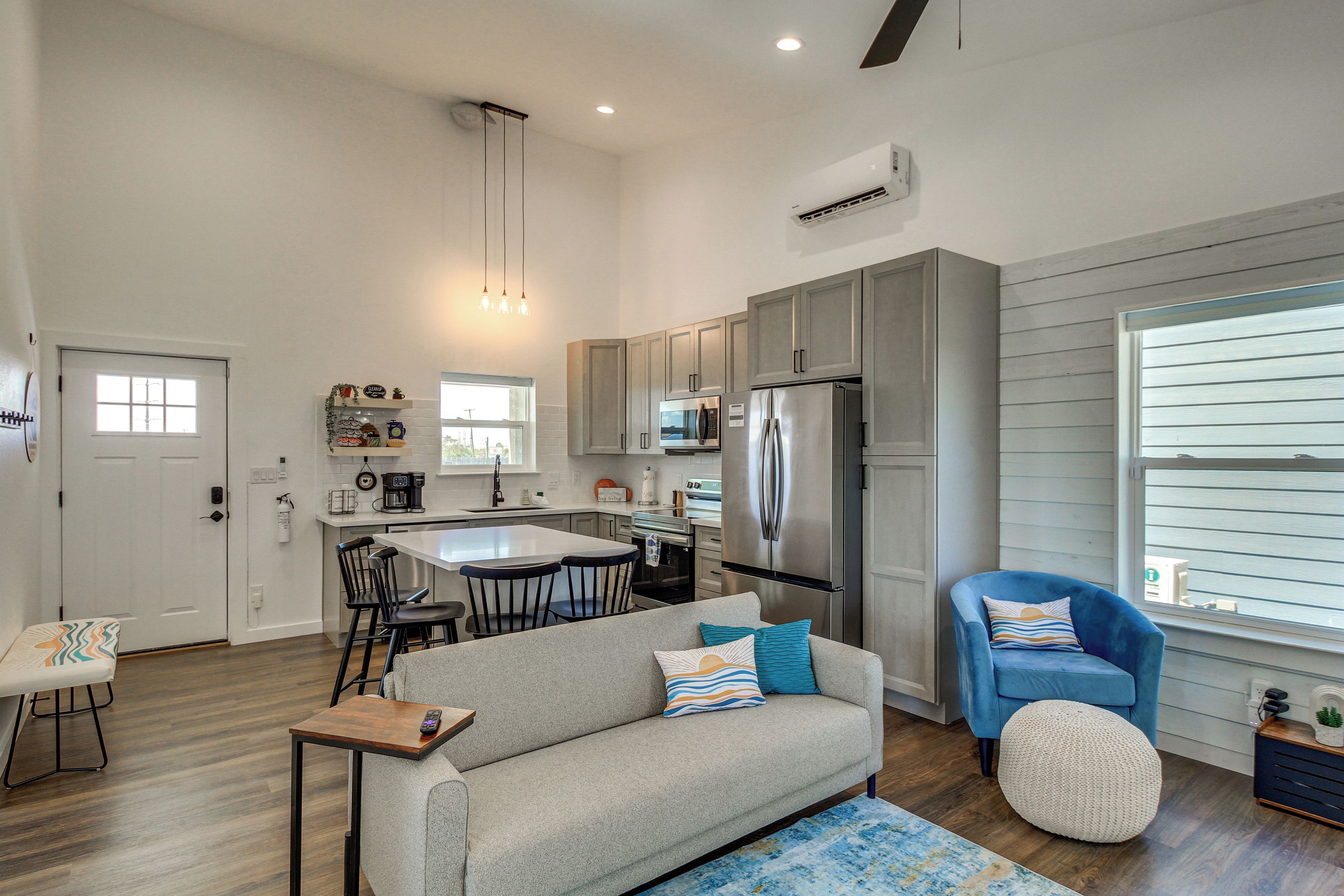 A modern kitchen with a central island, stainless steel appliances, and a dining area with a sofa and chairs.