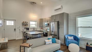A modern kitchen with a central island, stainless steel appliances, and a dining area with a sofa and chairs.