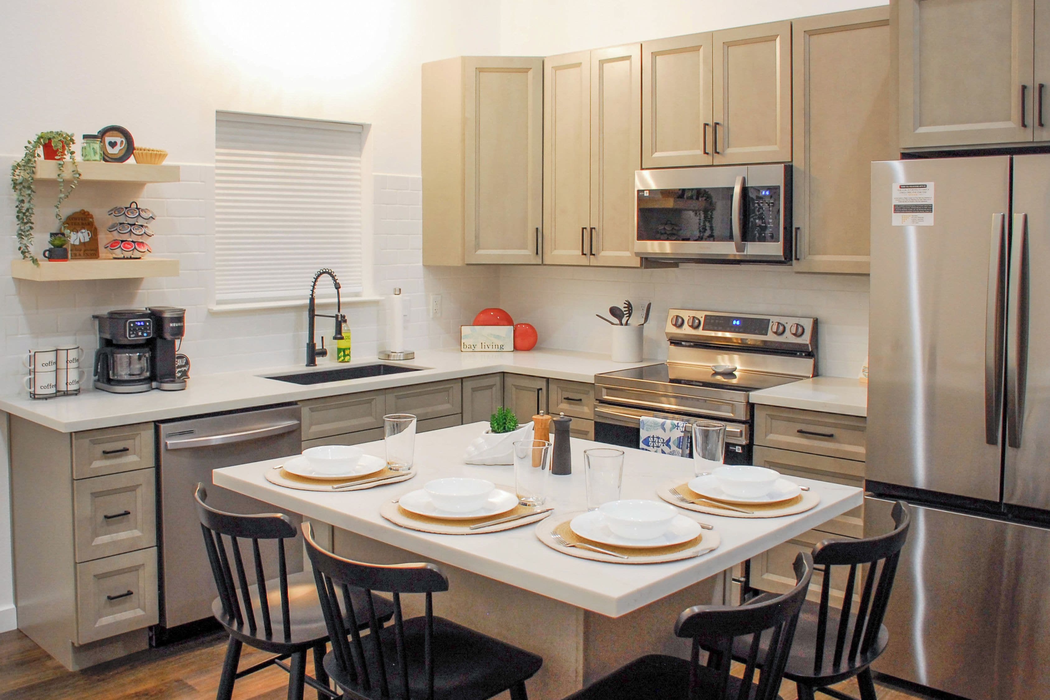 Una cocina moderna con una mesa de comedor preparada para cuatro personas, equipada con microondas, horno y refrigerador.