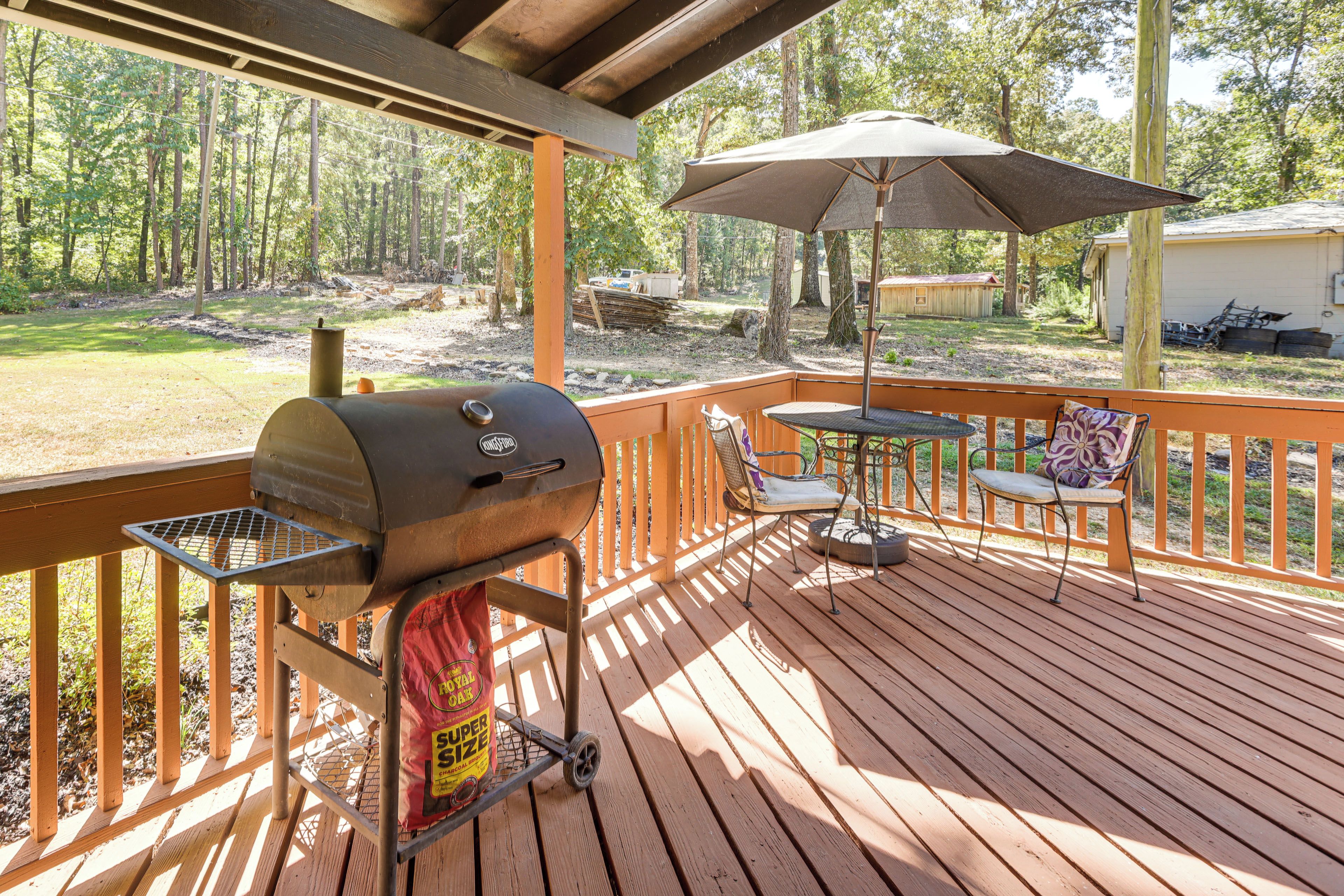 A covered outdoor deck with a grill, a table with chairs, and an umbrella.