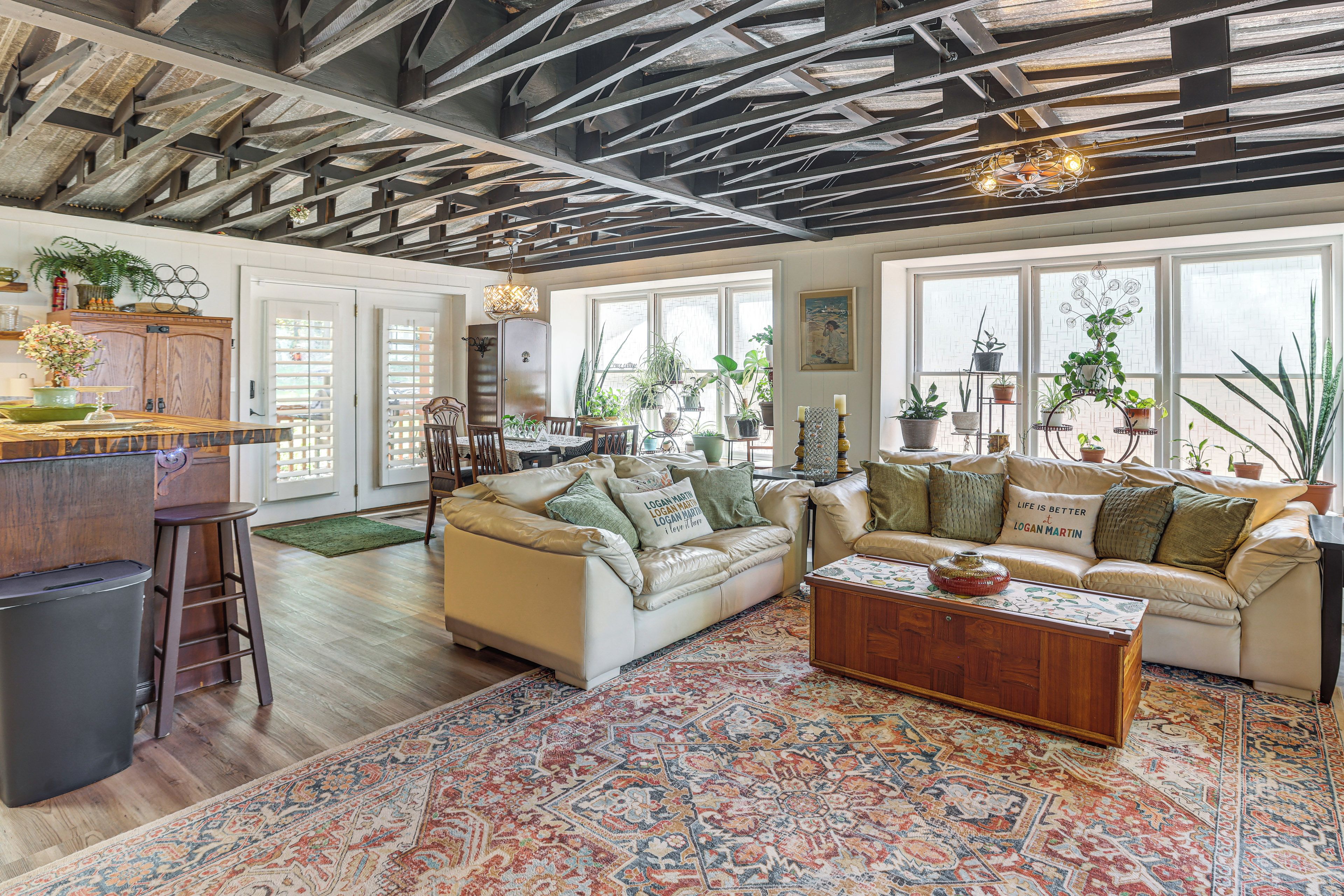 A spacious living room with a high ceiling, a patterned rug, and multiple seating areas.