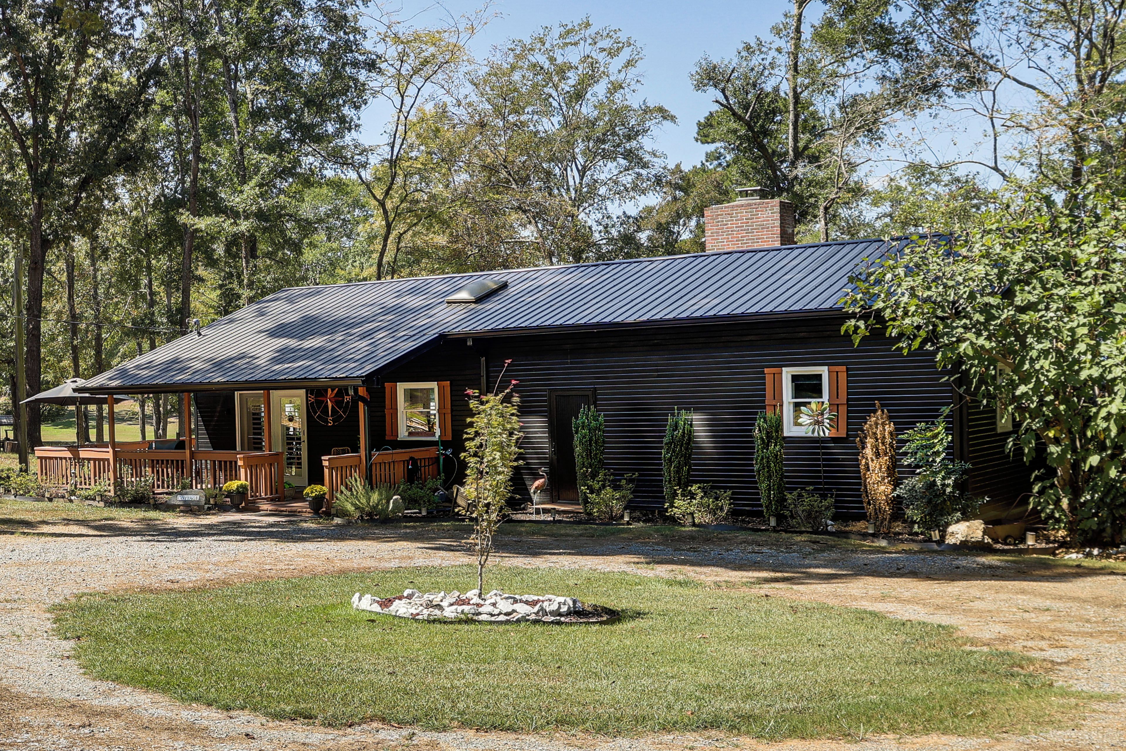 A rustic cabin with a sloped metal roof, wooden siding, and a porch with outdoor seating.