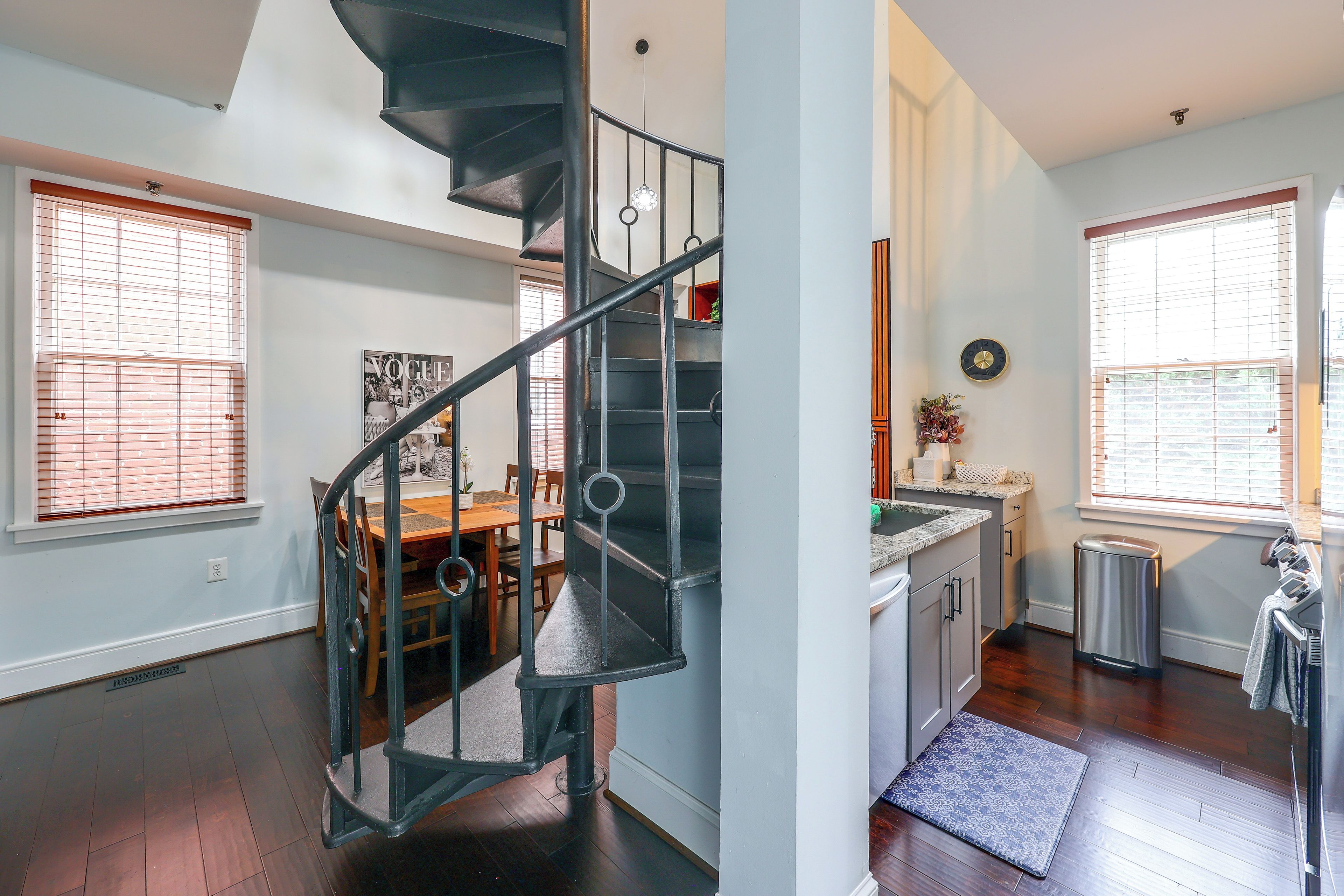 A modern interior with a spiral staircase, a dining area, and a kitchen with a view.