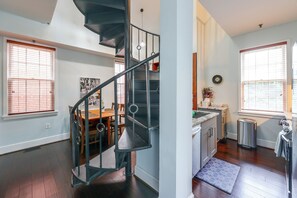 A modern interior with a spiral staircase, a dining area, and a kitchen with a view. - Walk to Waterfront! Old Town Alexandria Escape (Alexandria)
