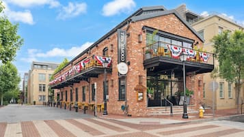 A brick building with a storefront, outdoor seating, and American flags.