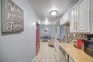 Una cocina con gabinetes blancos, un refrigerador rojo, salpicadero de azulejos y un letrero en la pared.