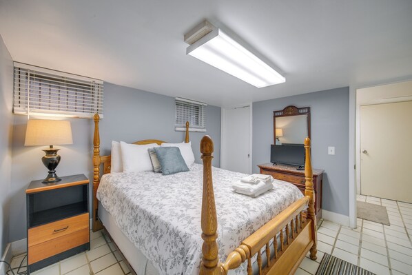 Un dormitorio con cama, mesitas de noche, lámpara, espejo y televisor.
