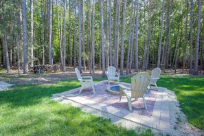 Uma área de estar externa com cadeiras Adirondack e uma lareira.