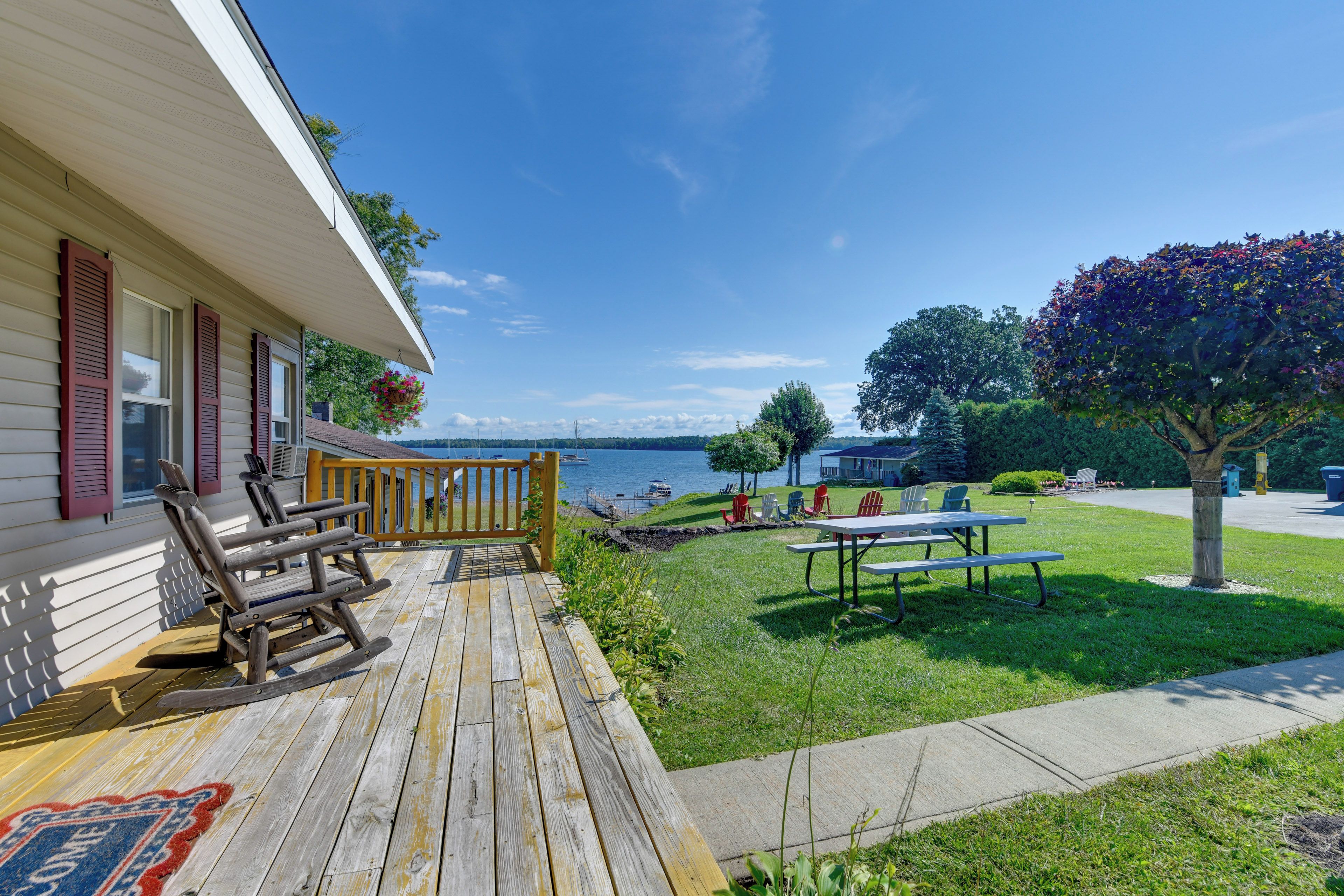 A wooden deck with outdoor furniture, a grassy lawn, and a view of the water.