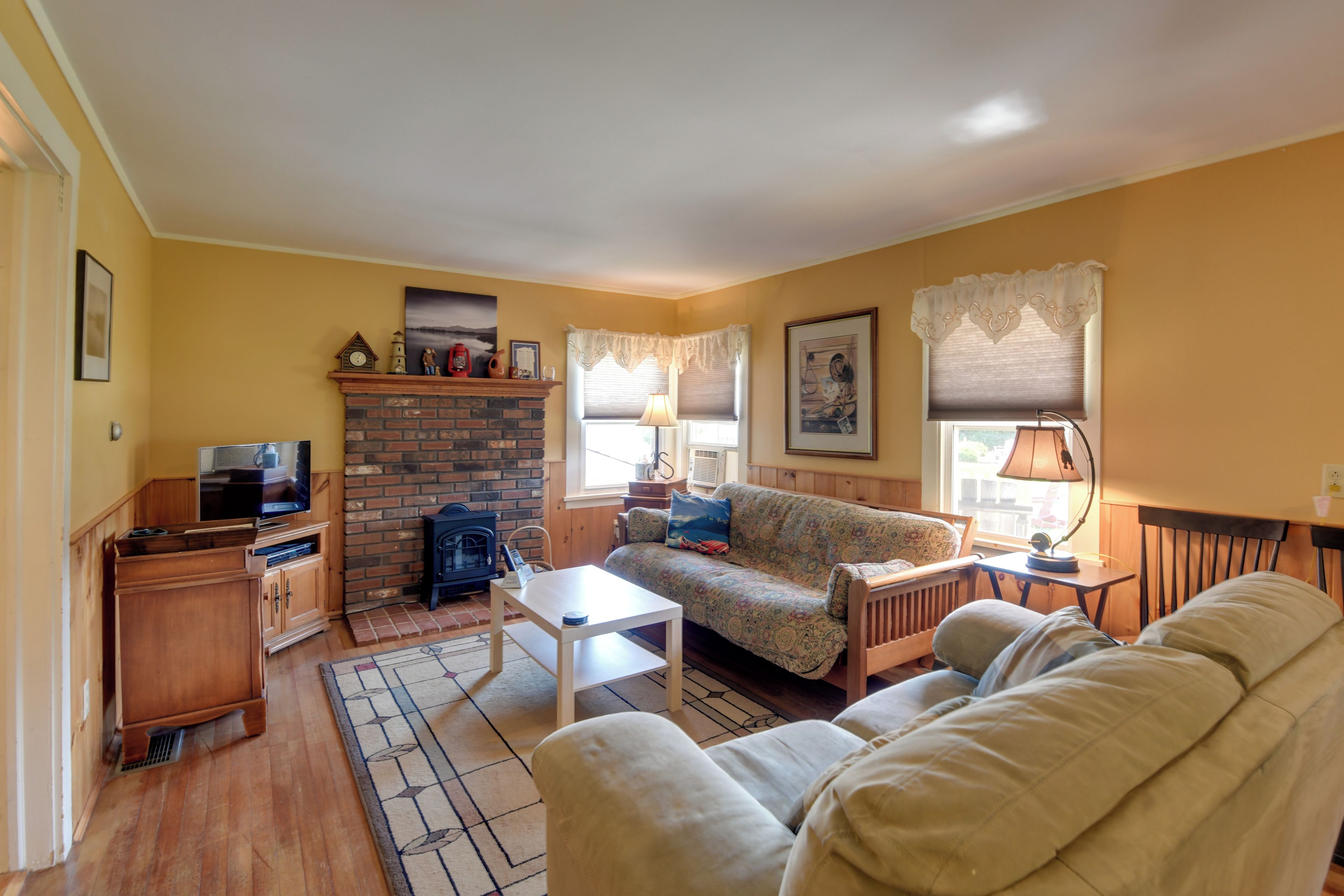 A cozy living room with a fireplace, a sofa, a television, and a table.