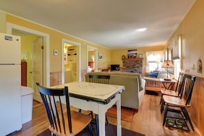 A compact living space with a dining table, chairs, a sofa, a television, and a kitchen area with a refrigerator and cabinets. - Private Beach Access! Lake Champlain Cabin (Plattsburgh)