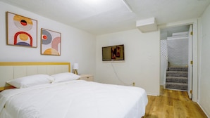 Quarto com cama, mesa de cabeceira, abajur e obras de arte na parede.