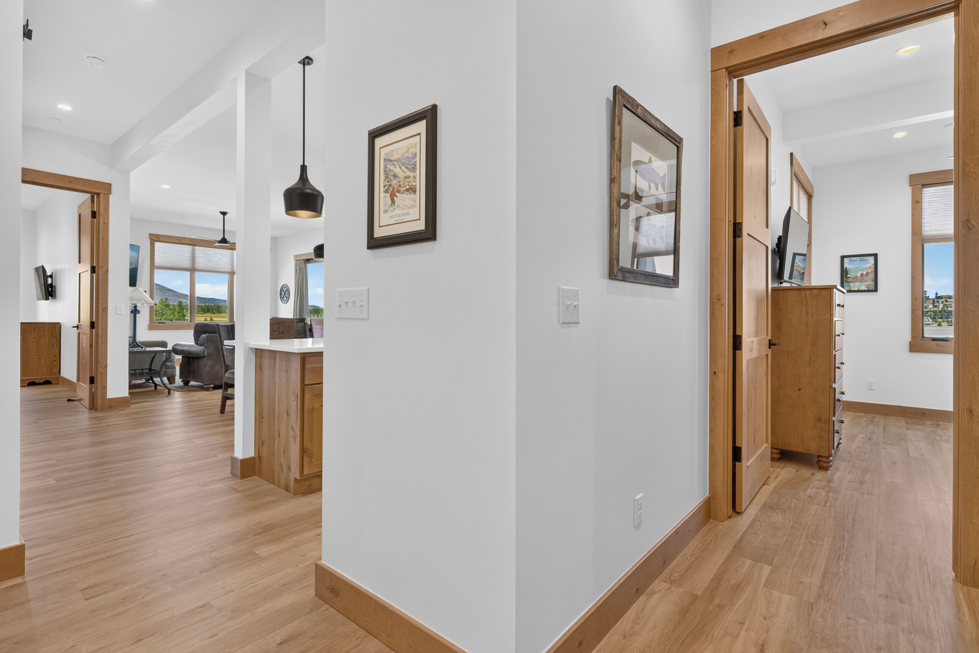 A spacious hallway with wooden flooring, a desk with a computer, and framed pictures on the walls.