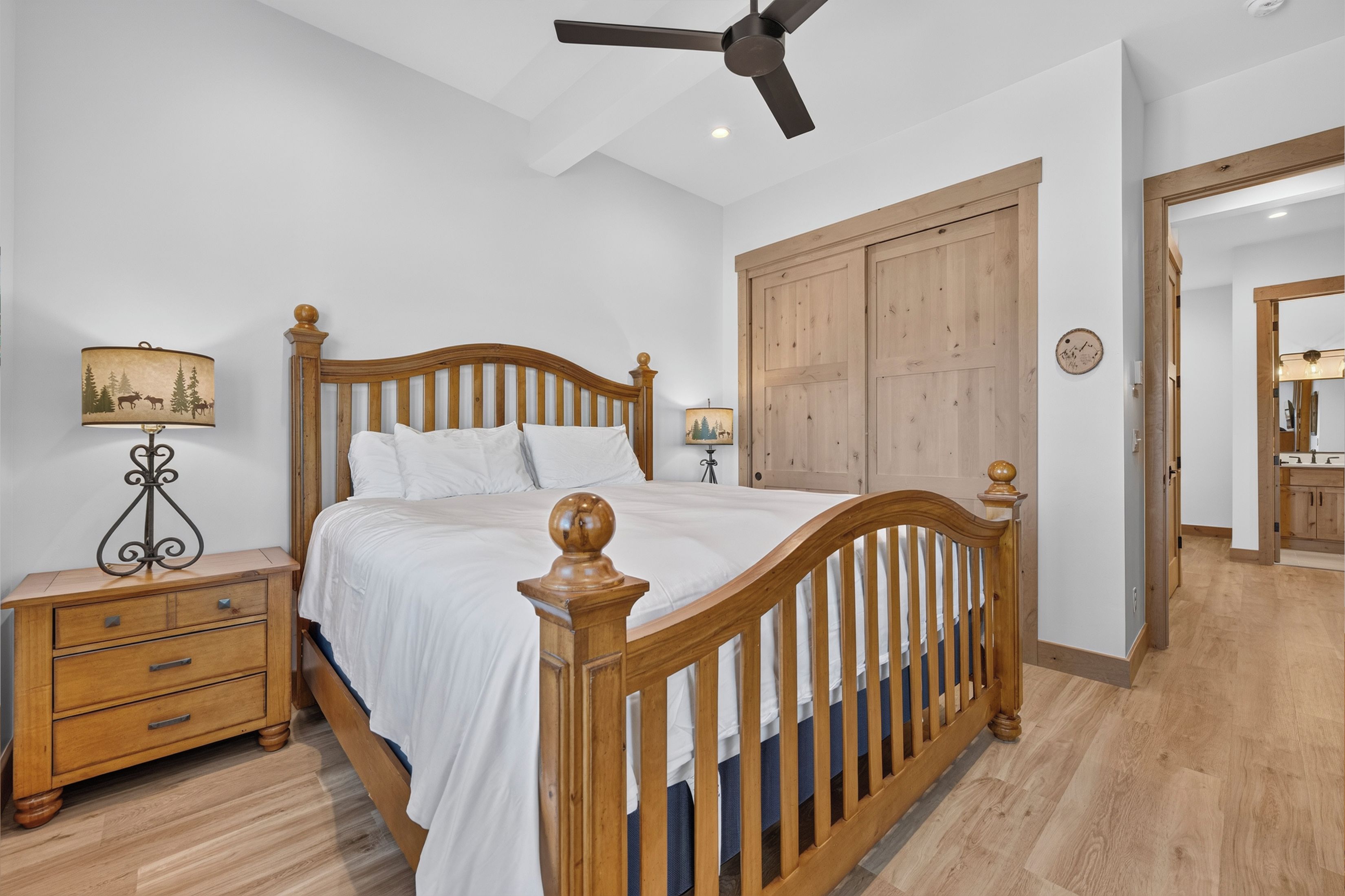 A bedroom with a wooden bed, nightstands, a ceiling fan, and a wardrobe.
