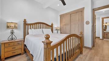A bedroom with a wooden bed, nightstands, a ceiling fan, and a wardrobe.