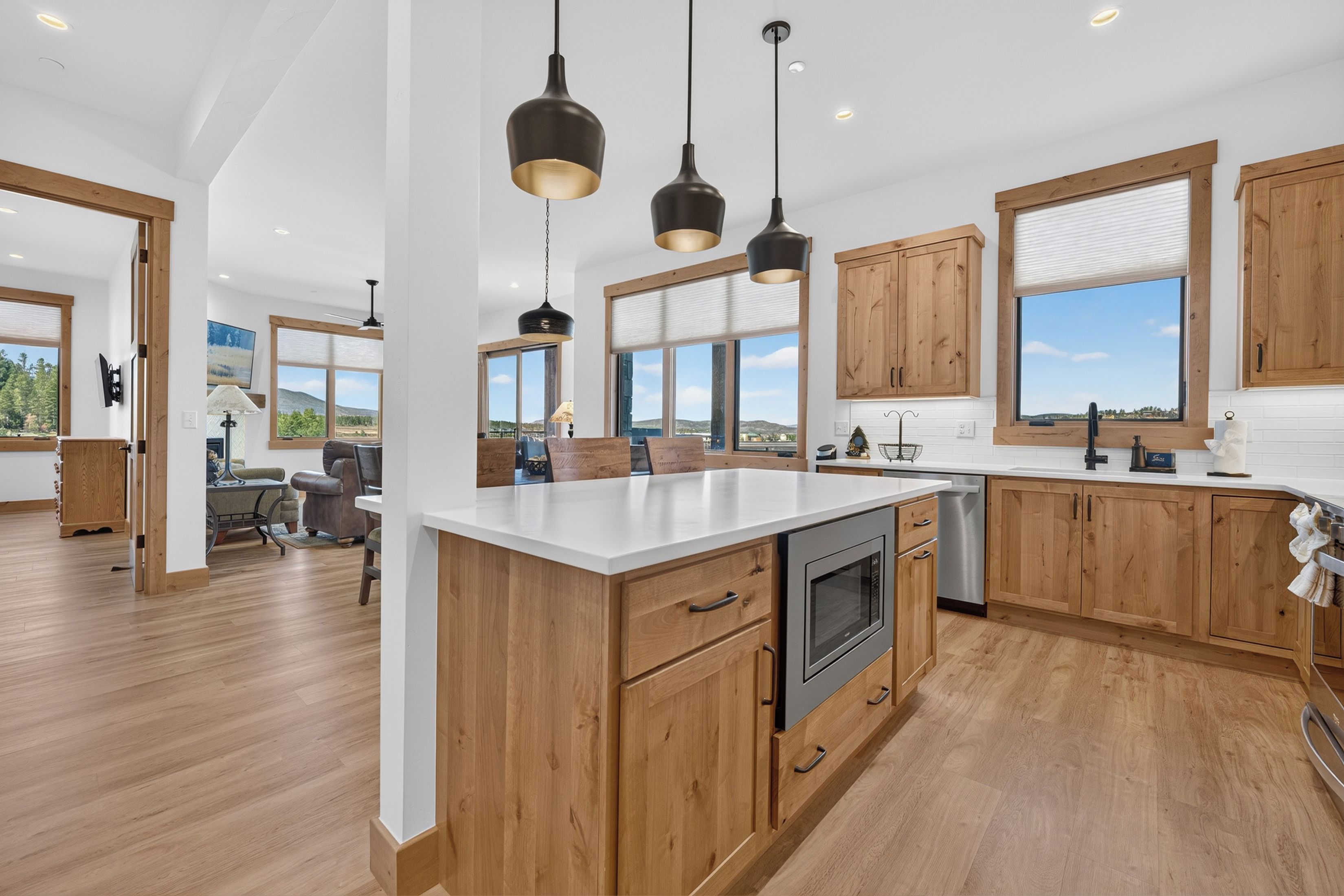 A modern kitchen with wooden cabinets, a central island, and pendant lighting.