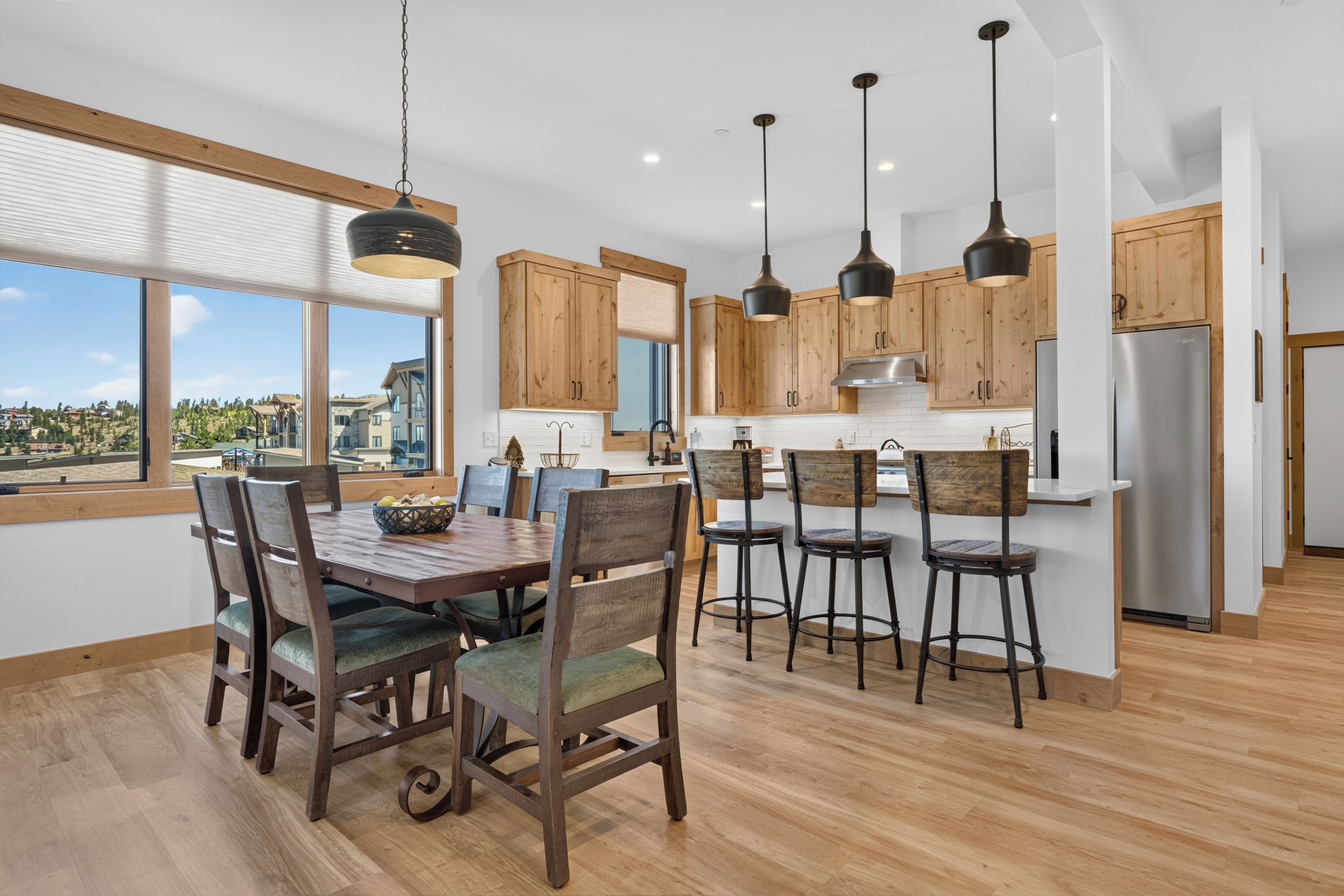 A modern kitchen with wooden cabinets, a central island, and pendant lighting.