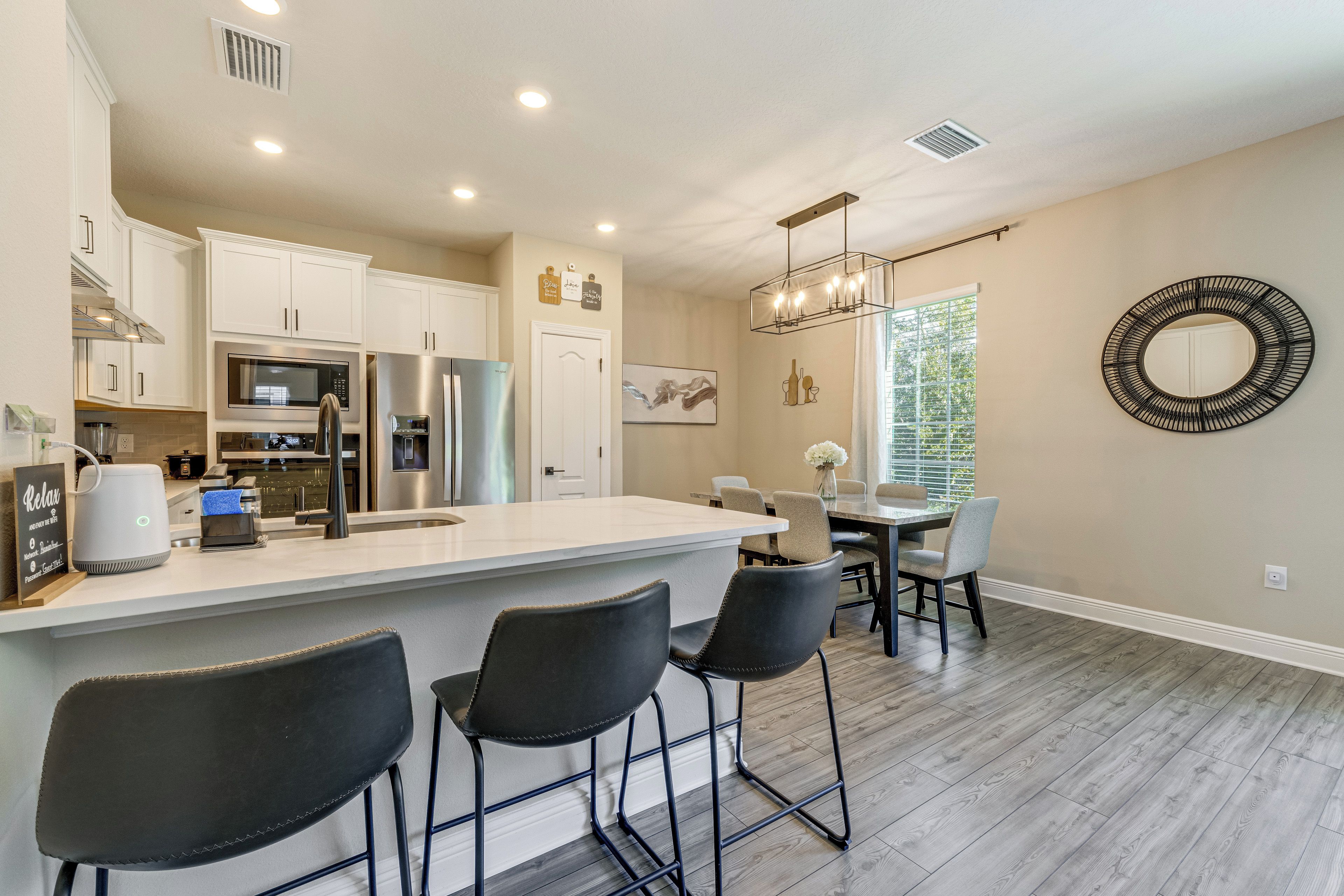A modern kitchen with a central island, bar stools, and a dining area with a table and chairs.