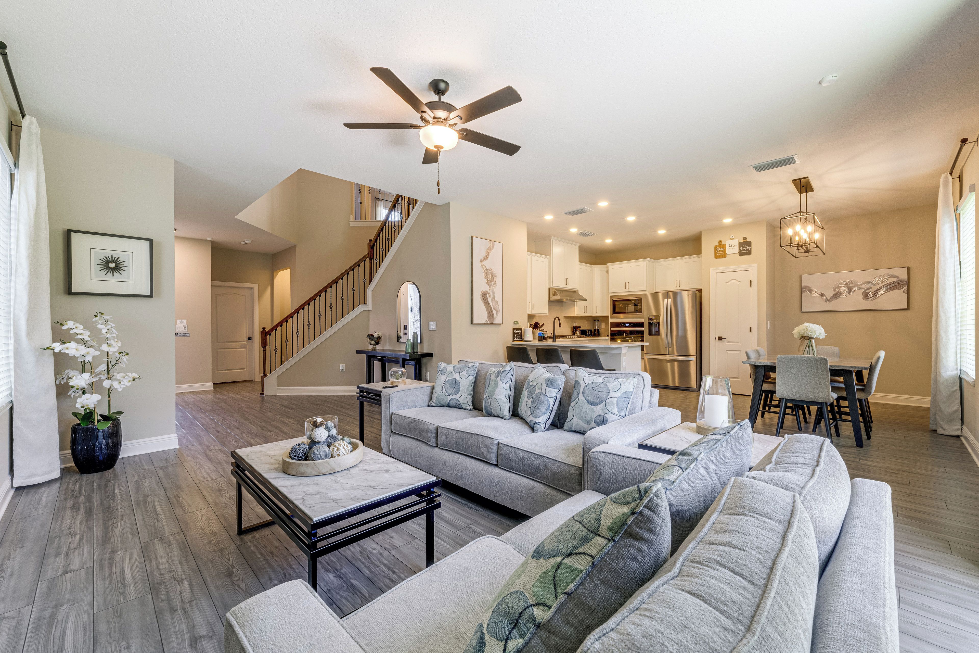 A modern living room with a gray sofa, a coffee table, and a ceiling fan.
