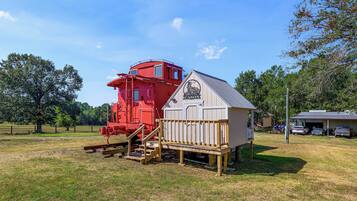 A red train engine and a white building with a ramp and stairs.