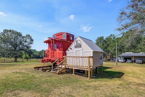 A red train engine and a white building with a ramp and stairs. - Converted Caboose on 50 Acres! Unique Naples Gem (Omaha)