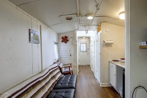 Un pasillo estrecho con un banco, una puerta que da a una habitación y una zona de kitchenette.