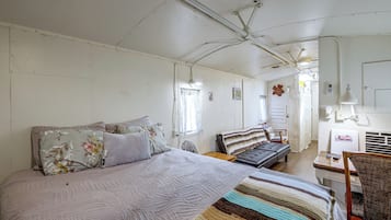 A room with a bed, a chair, a table, and a wall with a picture.