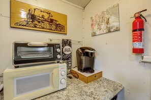 Uma cozinha compacta com torradeira, cafeteira e extintor de incêndio na parede.