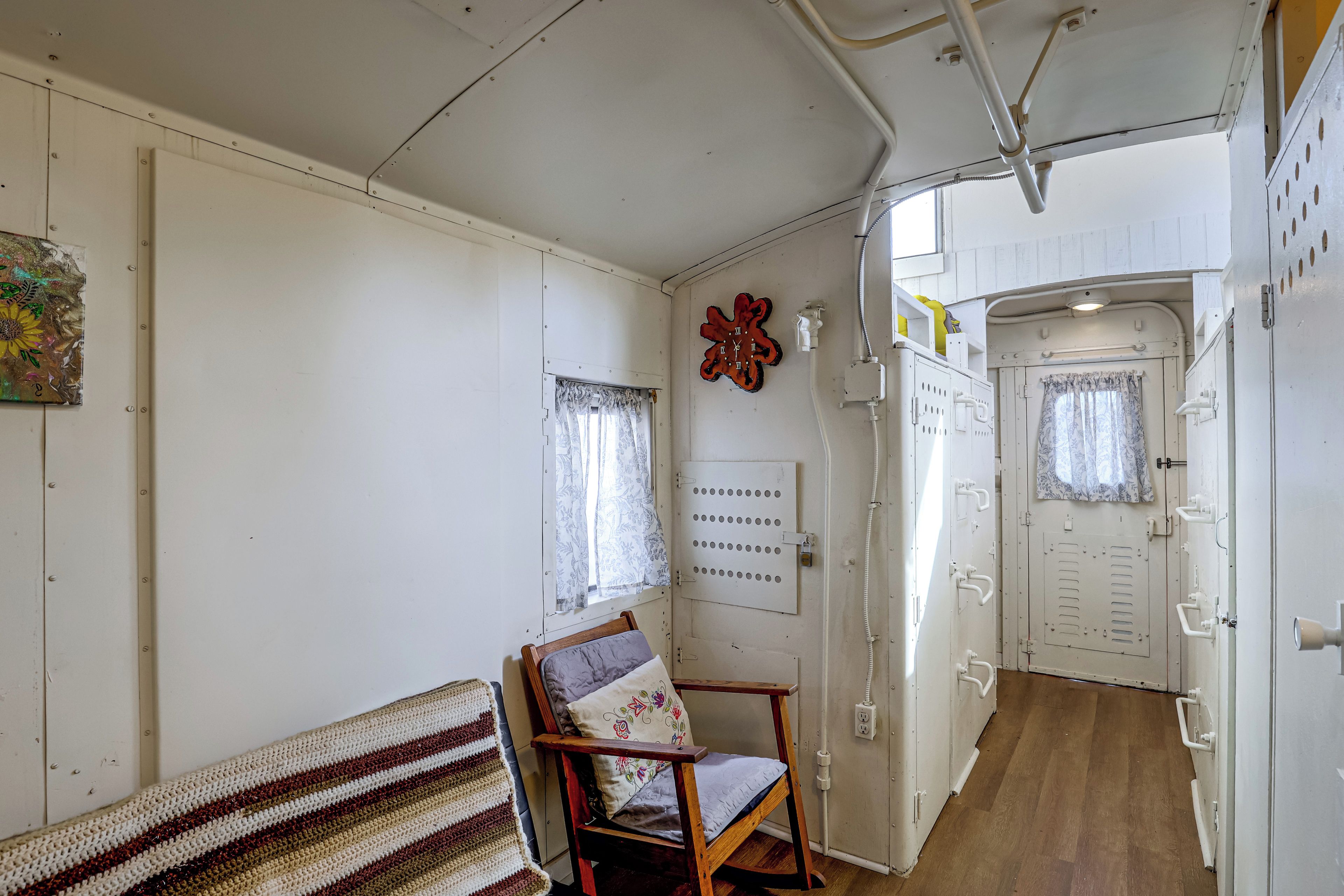 A room with a wooden chair, a patterned rug, a clock, and a door leading to another room.