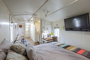 A compact room with a bed, a desk, and a television. - Converted Caboose on 50 Acres! Unique Naples Gem (Omaha)