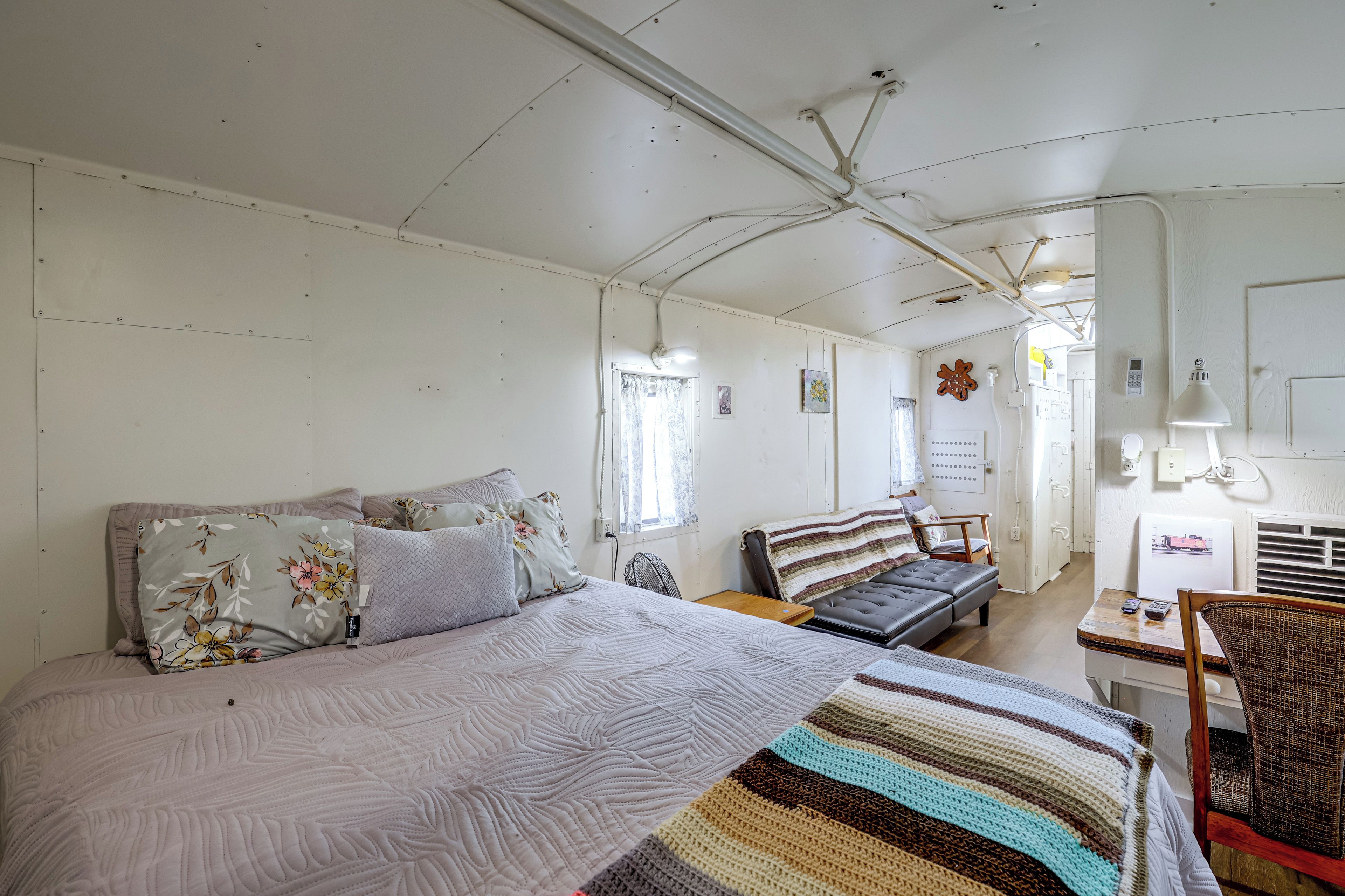 Una habitación con una cama, una silla, una mesa y una pared con un cuadro.