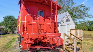 Un vagón de tren rojo con una pequeña construcción de madera a su lado.