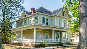 A two-story house with a front porch, a chimney, and a green door.