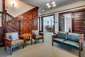 A spacious living area with a wooden staircase, a leather sofa, and a dining table with chairs. - 'agnes Arbor' Walkable Group Getaway in Decatur! (Decatur)