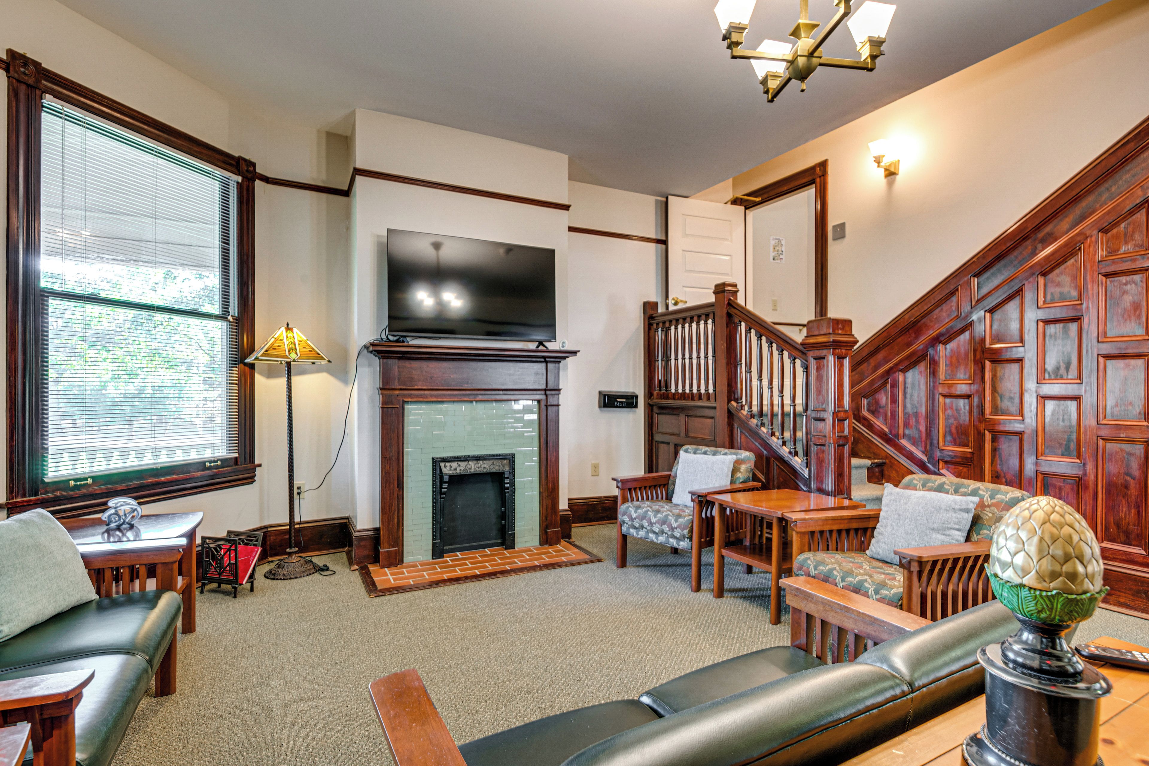 A living room with a fireplace, a television, a staircase, and a seating area.