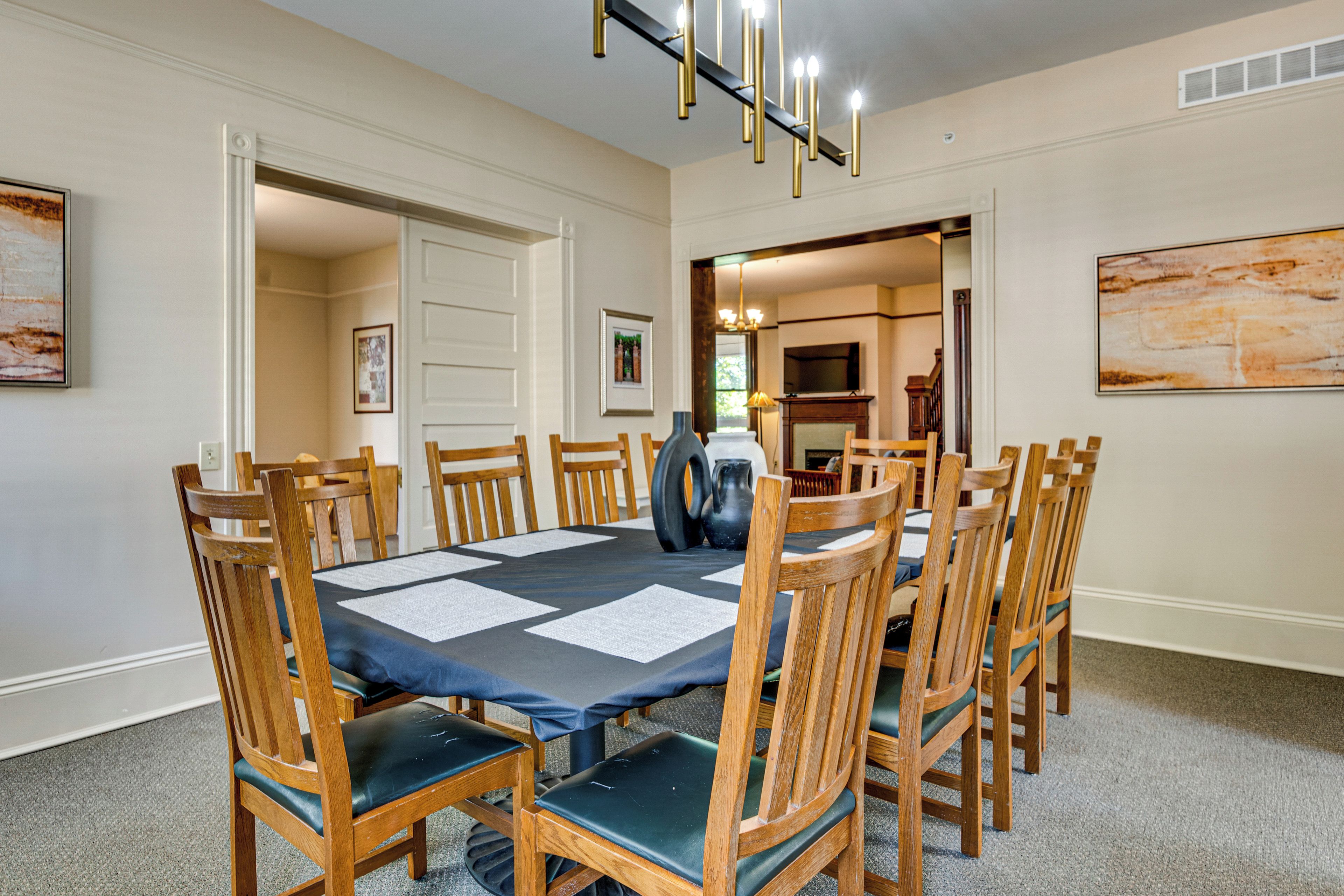 A dining room with a round table, wooden chairs, and a chandelier.