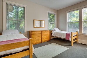 Un dormitorio con dos camas individuales, un aparador de madera, un espejo y una ventana con persianas.