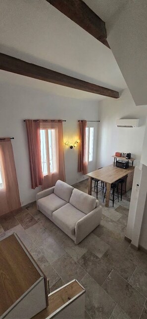 A living room with a sofa, a dining area with a table and chairs, and a kitchen area with a countertop and appliances. - Exploring La Ciotat on Foot • Harbor, beach, Calanques, and climate (La Ciotat)