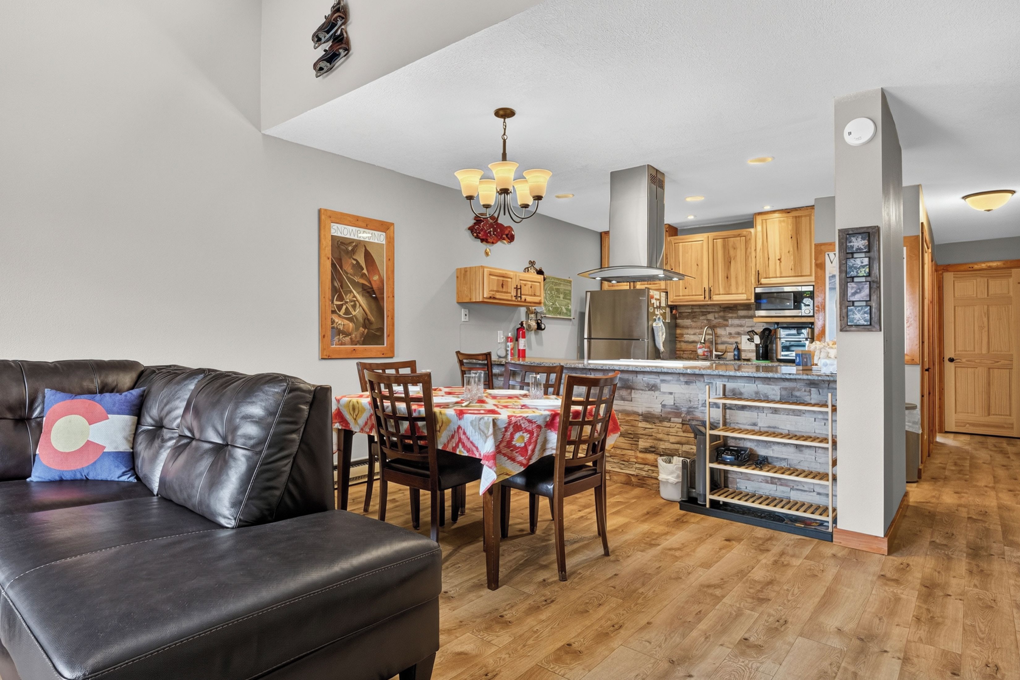 A modern kitchen with wooden cabinets, a central island, and a dining area with a table and chairs.