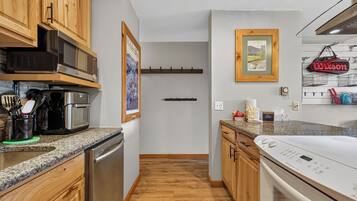 A modern kitchen with wooden cabinets, stainless steel appliances, and a granite countertop.