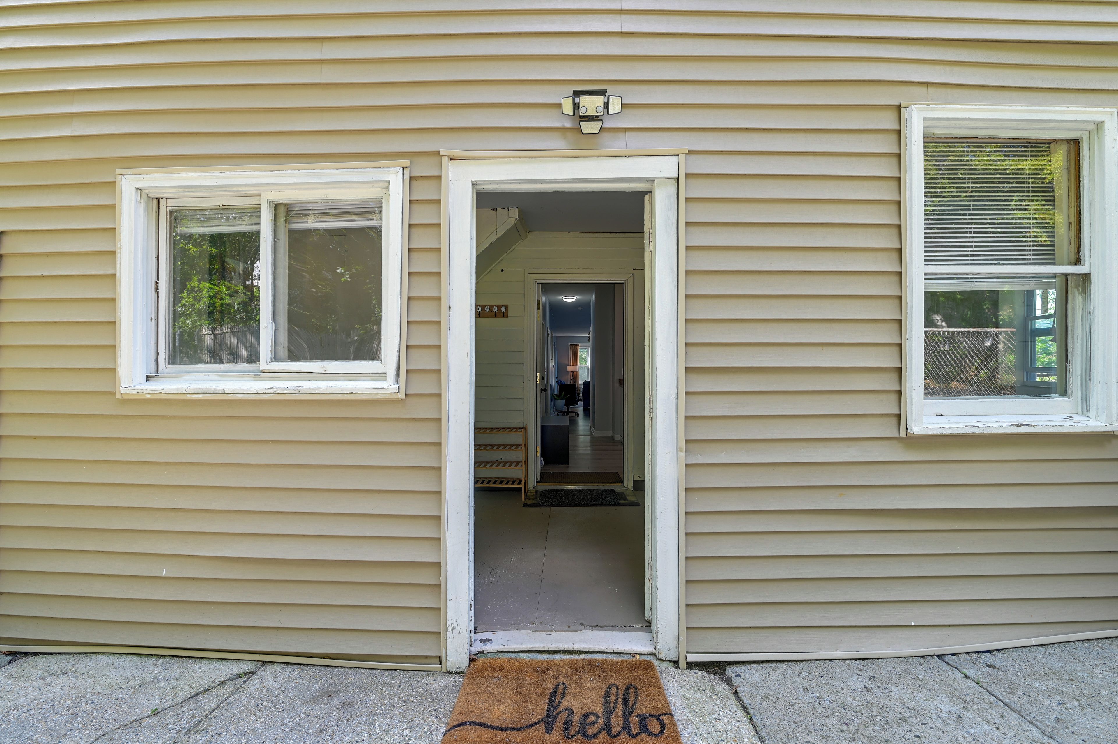 A house with a front door open, revealing an interior with a hallway and a door to a room.