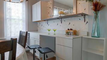 A modern kitchen with white cabinets, a bar area, and a dining table with chairs.