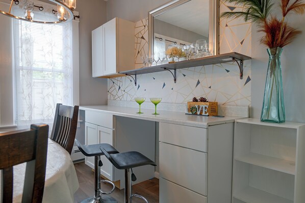 Una cocina moderna con armarios blancos, una barra y una mesa de comedor con sillas.