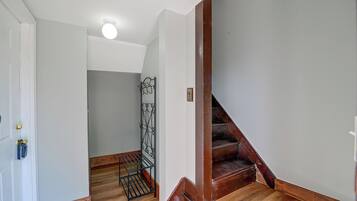 A hallway with a wooden staircase, a metal gate, and a white door.
