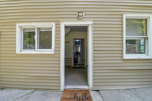 Una casa con la puerta principal abierta, mostrando un interior con un pasillo y una puerta que da a una habitación.
