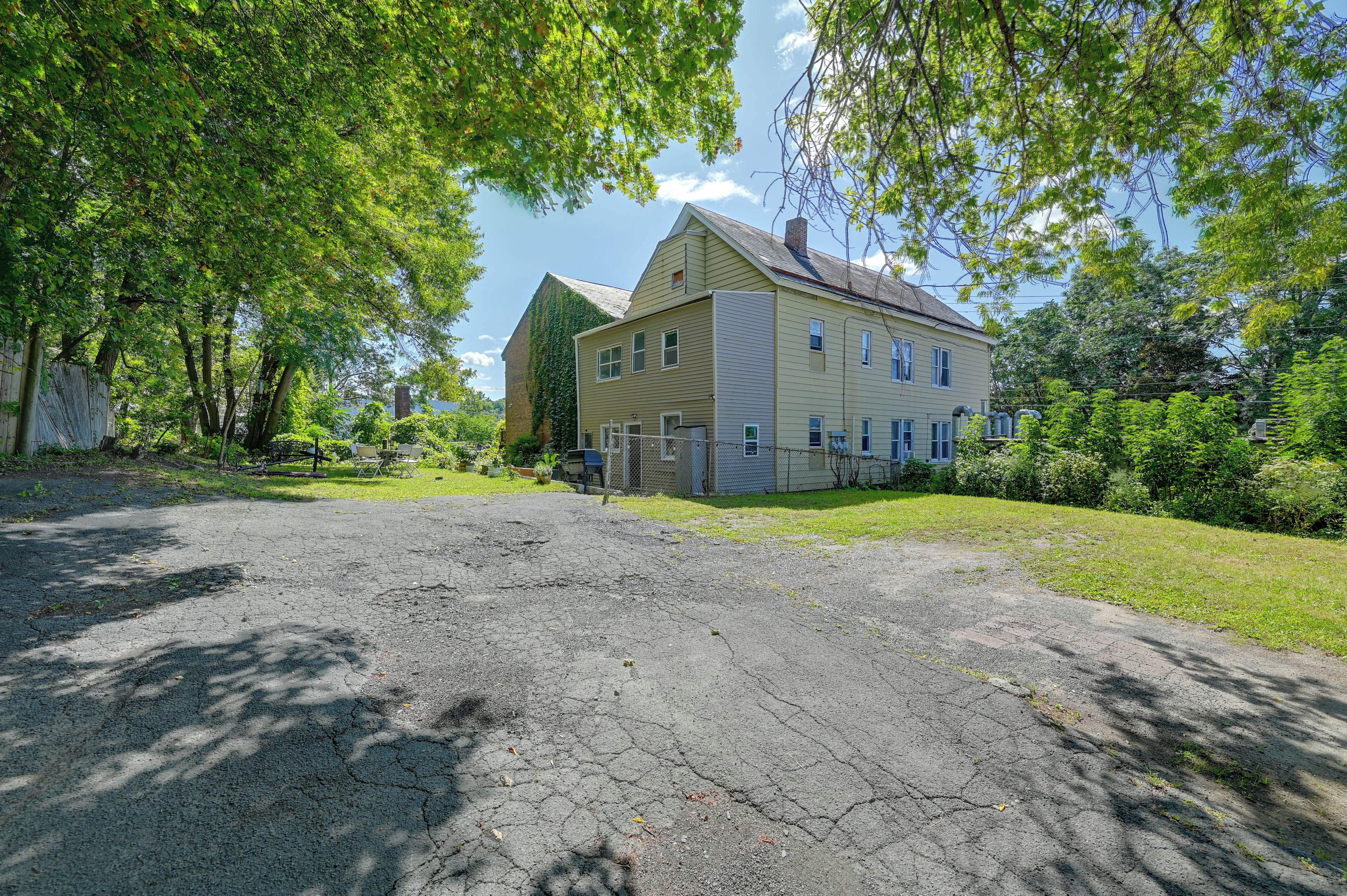 A two-story house with a large front yard and a paved driveway.