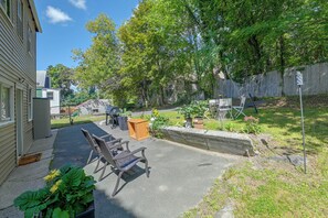 A residential backyard with a paved patio, outdoor furniture, and potted plants.