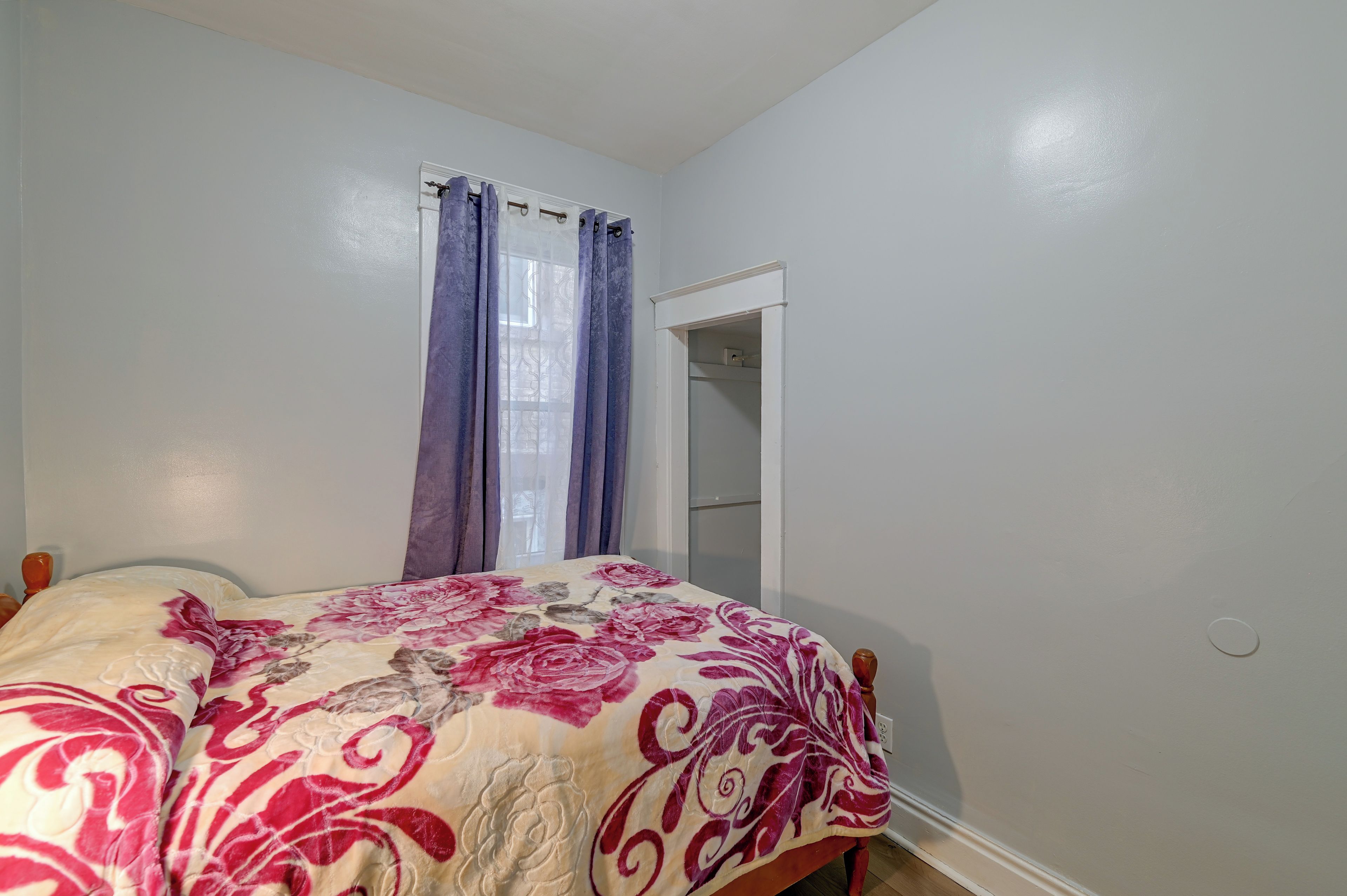 A bedroom with a bed, a wardrobe, and a window with curtains.