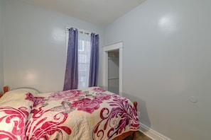 A bedroom with a bed, a wardrobe, and a window with curtains.