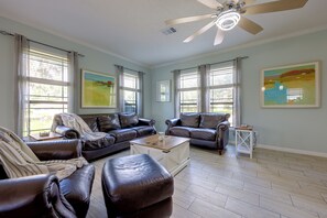 A living room with a ceiling fan, leather sofas, a coffee table, and artwork on the walls. - Waterfront Interlachen Retreat w/ Dock on Lake Ida (Interlachen)